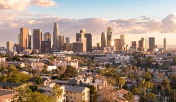Sun-filled photograph of downtown Los Angeles skyline during the day.