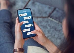 Photo zoomed in on a woman holding a phone and looking at text messages.
