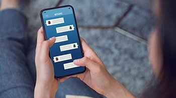 Photo zoomed in on a woman holding a phone and looking at text messages.