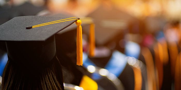 Photograph of a line of several students in graduation caps and gowns, facing away from the camera, and report title: Supporting Young People’s Food Security: CalFresh Participation During and After High School