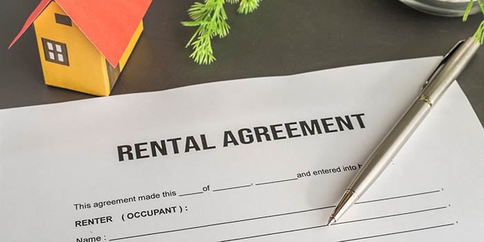 Photo shows a rental contract with a pen on it, and a small toy house above it.