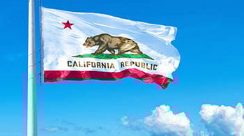 Photo of California flag with blue skies in the background.