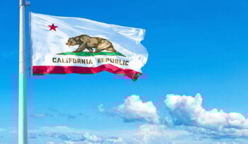 Photo of the California flag with blue skies in the background