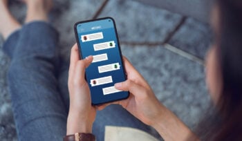 Photo zoomed in on a woman holding a phone and looking at text messages.