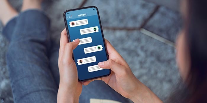 Photo zoomed in on a woman holding a phone and looking at text messages.