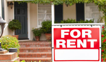 Sign says "FOR RENT" in front of a house