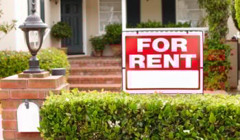 Sign says "FOR RENT" in front of a house