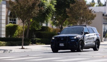 Photograph of a City of Corona police vehicle on a street with trees.