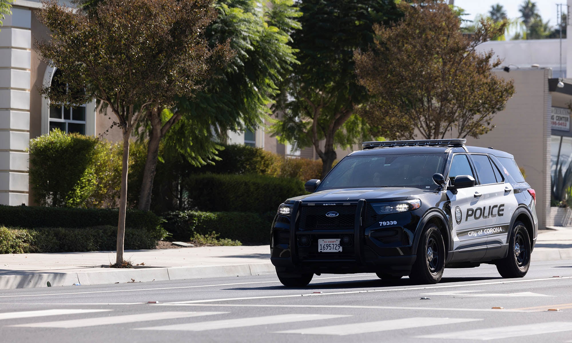 Photograph of a City of Corona police vehicle on a street with trees.
