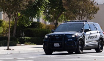 Photograph of a City of Corona police vehicle on a street with trees.