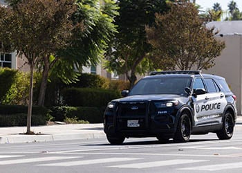Photograph of a City of Corona police vehicle on a street with trees.
