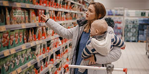 Mother and child buying in supermarket. Mom and her little son are in a grocery store shopping for food.