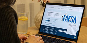 Photo of a person looking at a laptop screen, with the FAFSA website open