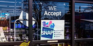 Sign on grocery store says "We Accept SNAP" Supplemental Nutrition Assistance Program