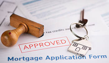 Photo of a mortgage application form marked "APPROVED" along with a set of keys