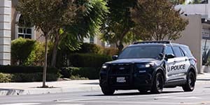 Photograph of a City of Corona police vehicle on a street with trees.