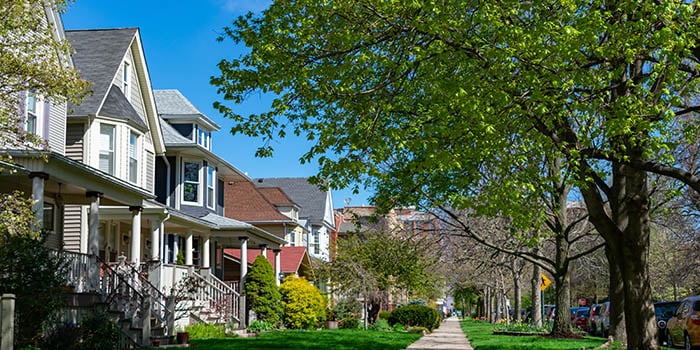 Photograph of a residential street with houses and trees.